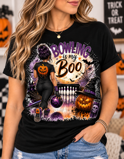 Black t-shirt with Halloween bowling graphic featuring a woman with a purple-streaked bun bowling toward pins, a glowing full moon with "Bowling is My Boo" text, bats, a jack-o'-lantern wearing a witch hat, and a skull tumbler