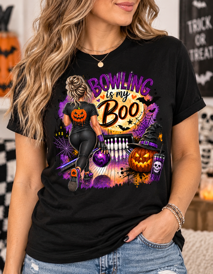 Black t-shirt with Halloween bowling graphic featuring a woman with a purple-streaked bun bowling toward pins, a glowing full moon with "Bowling is My Boo" text, bats, a jack-o'-lantern wearing a witch hat, and a skull tumbler