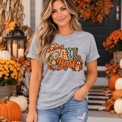 Woman wearing heather grey Fall Y'all Texas t-shirt with patchwork cowgirl hat, pumpkins and fall flowers design on a decorated autumn porch