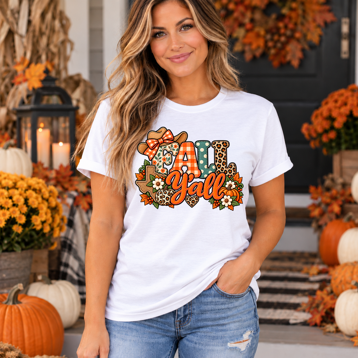 Woman wearing white Fall Y'all Texas t-shirt with patchwork cowgirl hat, pumpkins and fall flowers design on a decorated autumn porch